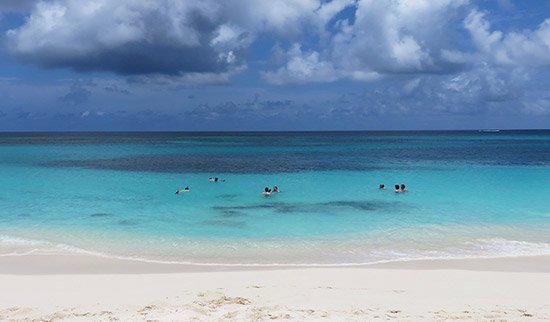 snorkeling in shoal bay in front of tropical sunset